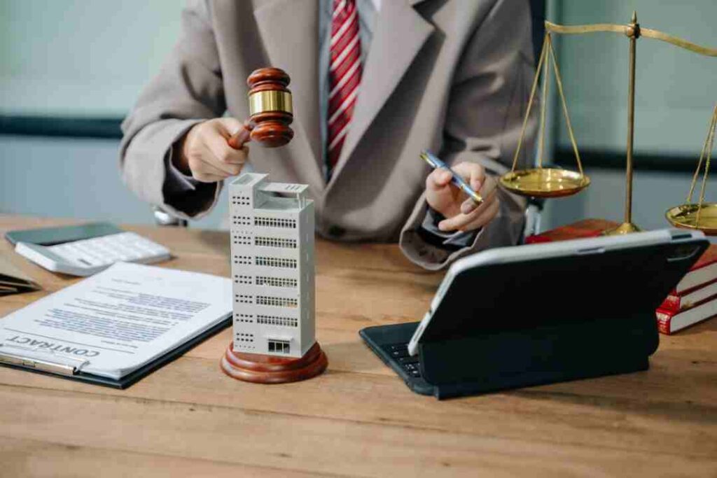 Lawyer holding gavel and pen over a contract and a model skyscraper.